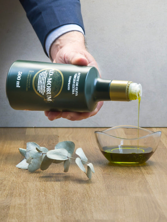 Botella de aceite de oliva virgen extra temprano de Ad-Morum de la que sale el aceite y se puede ver su color y tipo de goteo.